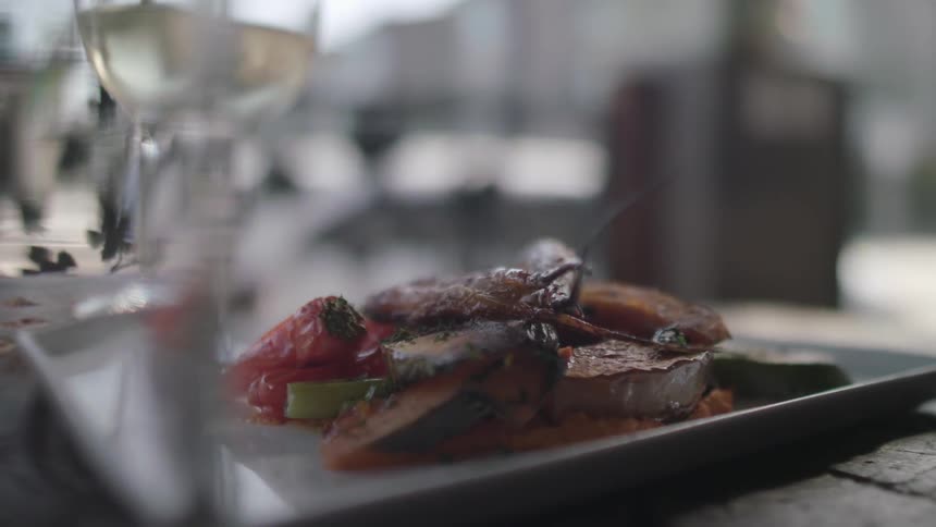 Plated food sits near a glass of white wine