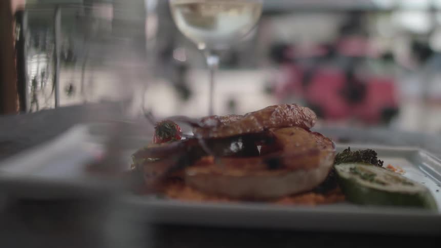 A plate of food and glass of wine sit on a counter