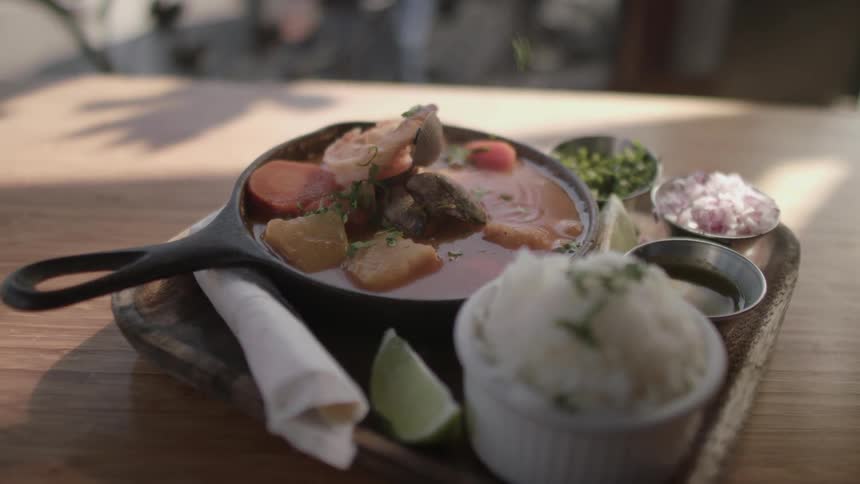 An herb is sprinkled onto a bowl of food