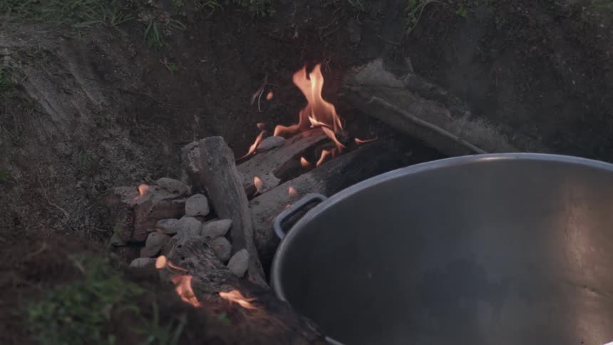 A pot cooks on an outdoor fire