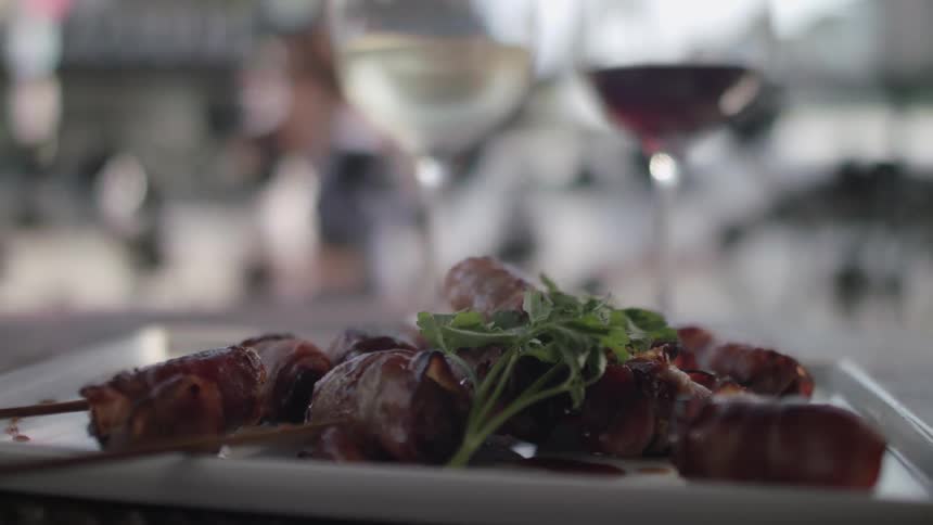 People outside a window walk past a plated meal with wine