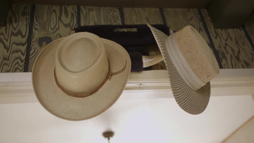 Cowboy hats hang on the wall above a door