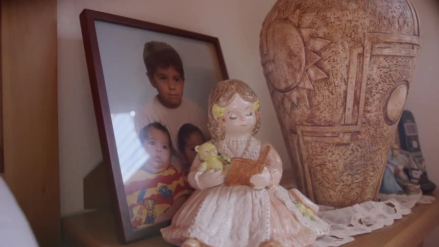 A porcelain figurine sits near a framed picture and vase