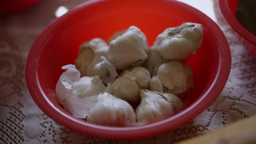 Garlic cloves sit in a red bowl