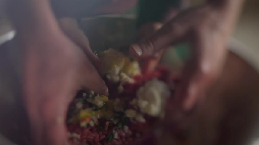 An adult and child stir food in a kitchen bowl