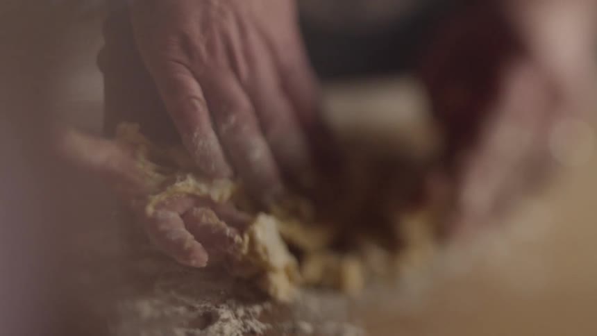 An adult helps a child knead and shape dough