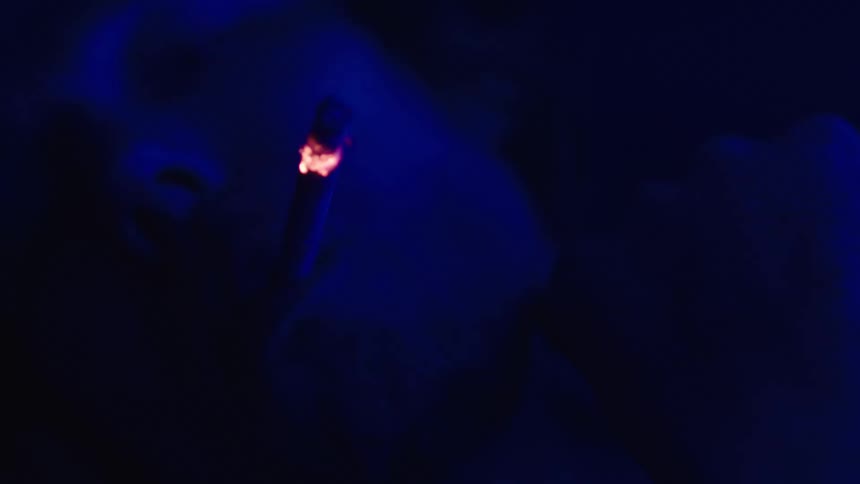 A man is smoking a cigarette in the dark