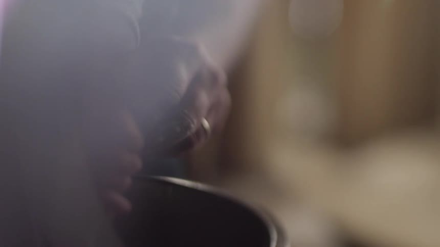 An adult helps a young child to stir ingredients in a bowl