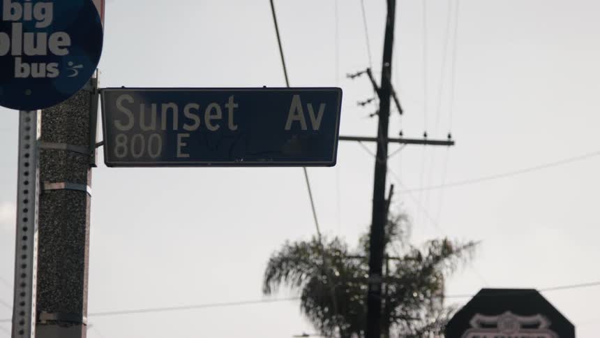 A sunset avenue sign hangs from a post