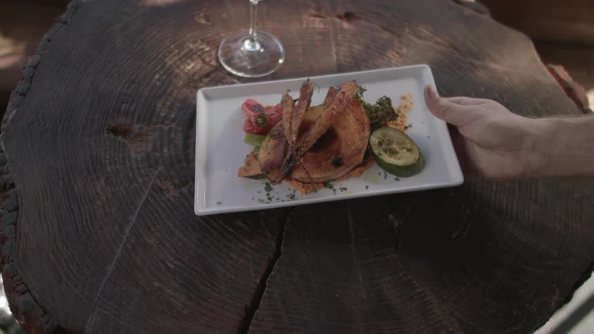 A plate of food is set on a table next to a glass of wine