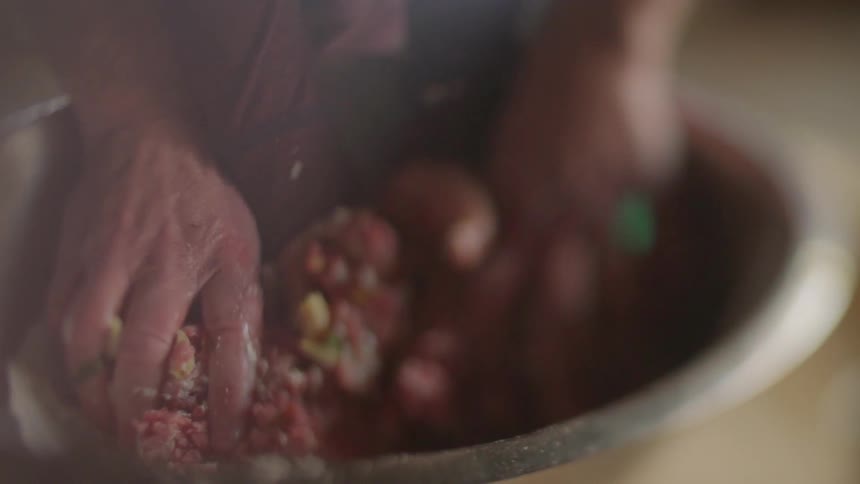 Person helping child to mix foods in bowl with their hands