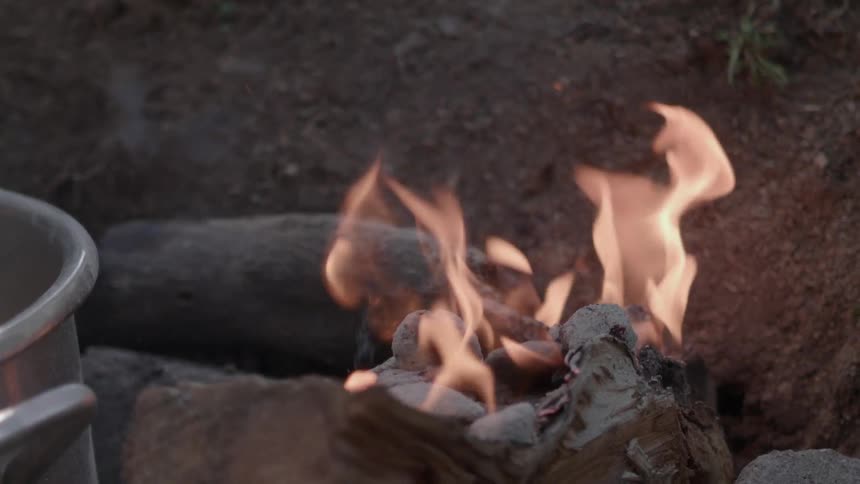 A large pot cooks on an outdoor fire