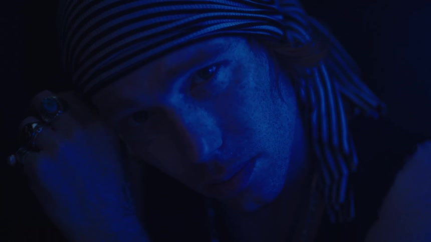 The man wipes the side of his face in the dark