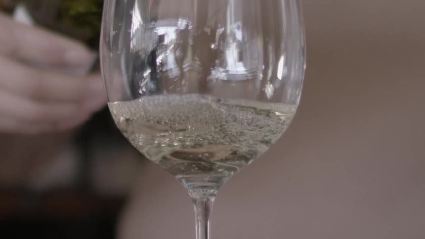 A glass is slowly filled with liquid