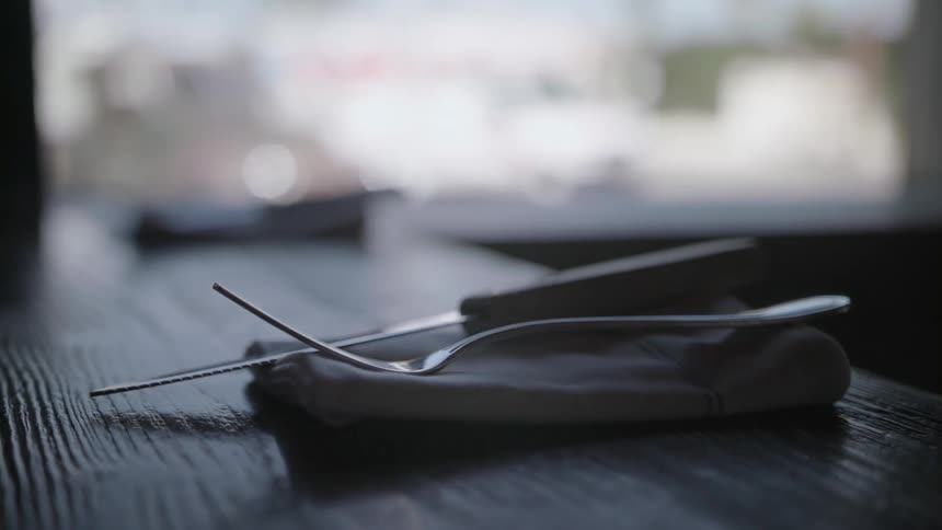 Fork and knife sitting on napkin on table next to window