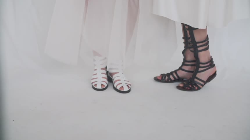 View of the feet of two women wearing strapped sandals while being photographed