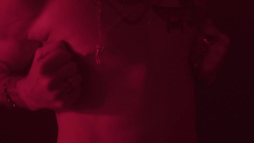 Redlit closeup of a tattooed arm and hand in a moody scene