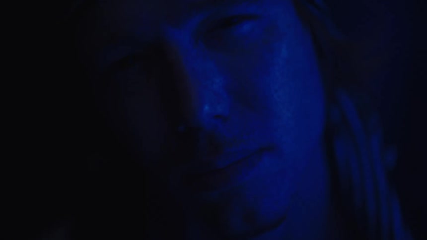 A man is shown in blue light with intense and emotional expressions