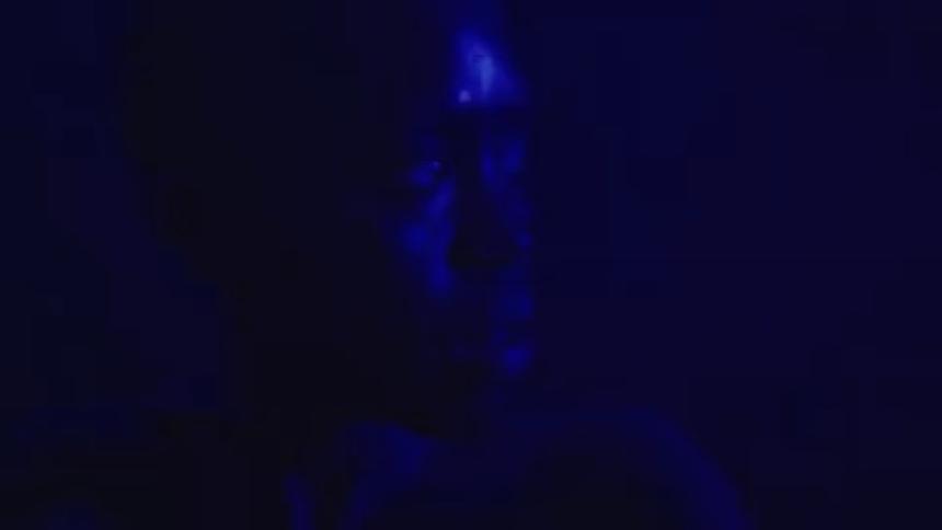 The woman looks all around in the dark room