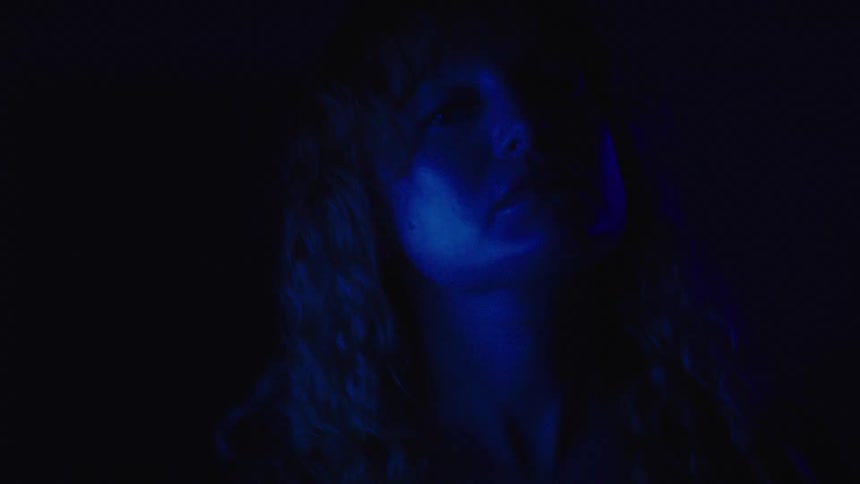 A woman moves her head around in the dark