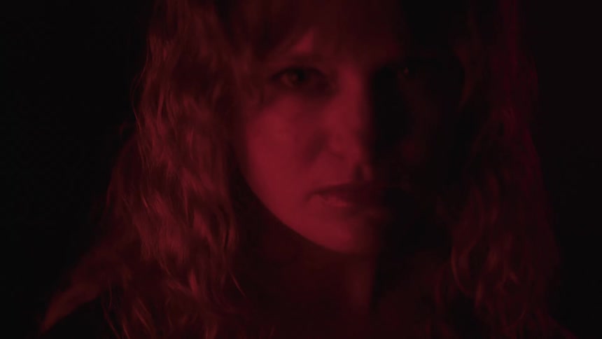 The woman is blinking in the room with red light