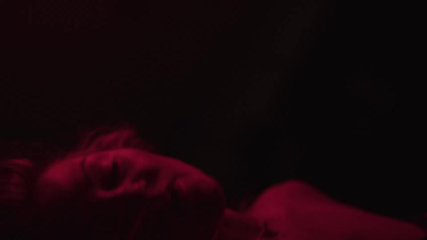 The woman dances under the red light in the dark room