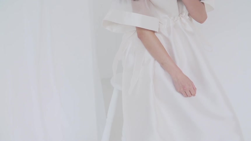 A woman wearing a white dress moving her arms around