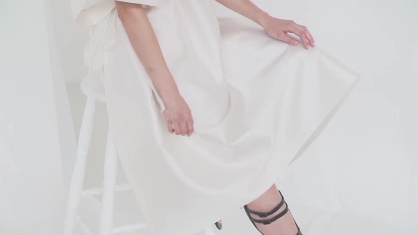 Woman wearing white dress moves her hands across it
