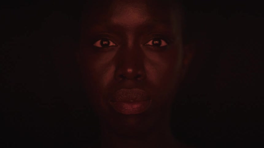 A light flickers on the womans face in the dark area