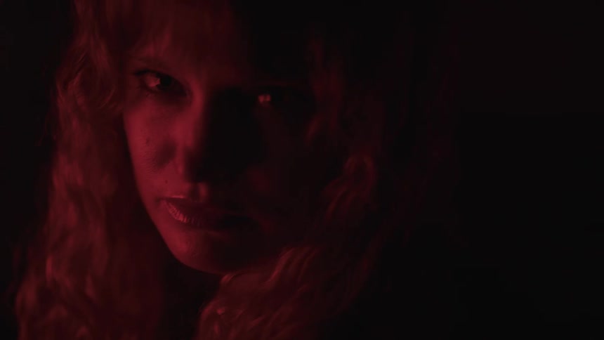 A close view of a woman with long light colored hair shows her looking off to her left with a serious expression then turning her head to face the camera