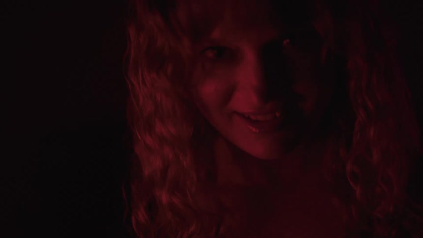 A woman in red light shows different facial expressions in a dark setting