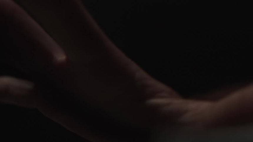 Hand closing and opening against a black background