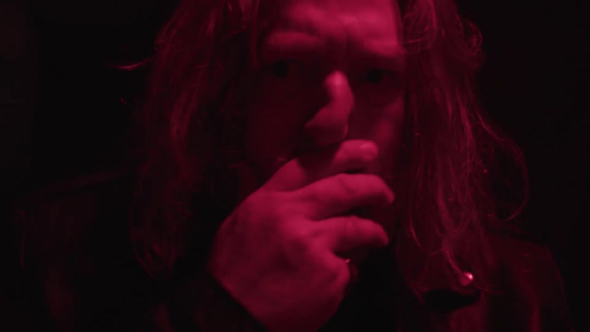 Longhaired man touches his face under intense red light
