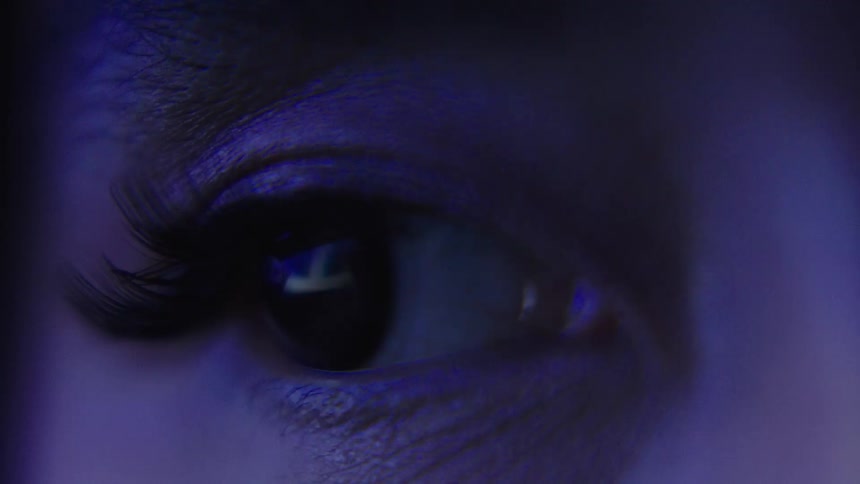 Closeup eye reflecting colorful lights in the environment