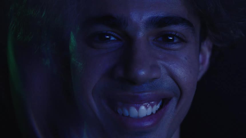 Face lit by blue light reveals a wide joyful smile