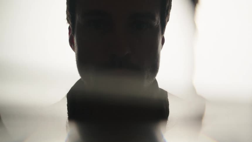 The mans face is in darkness as the light flashes