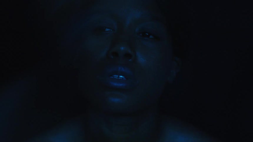 Closeup face illuminated by blue light in a dark setting