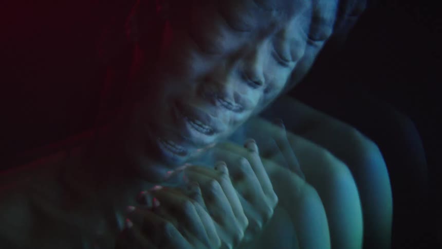 A woman is crying as lights flash on her face