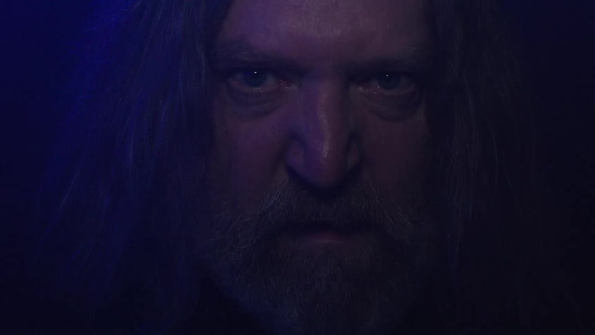 Man with intense gaze beard and long hair revealed in flashing lights