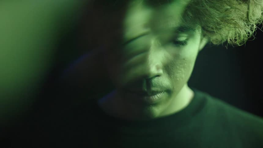 Male face partially lit by changing light colors