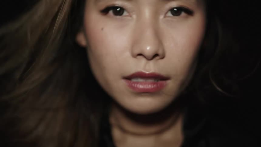 A lowlight closeup shot of a womans face with makeup and long hair