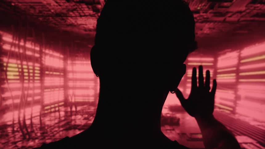 Silhouette of a person facing a glowing red panel with one hand raised