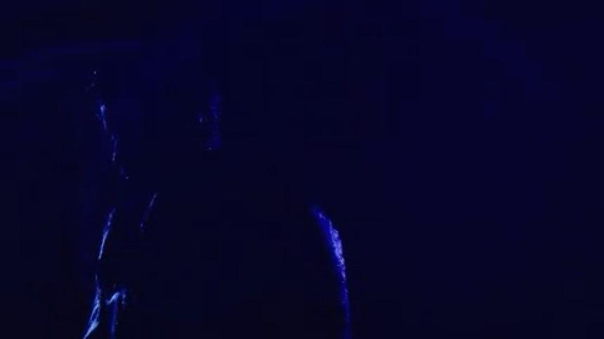 Human figure in silhouette illuminated by intense blue light at night and in the rain