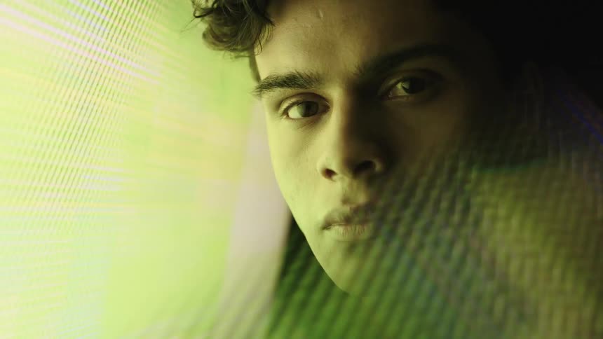 Young mans face lit by colorful digital light reflections