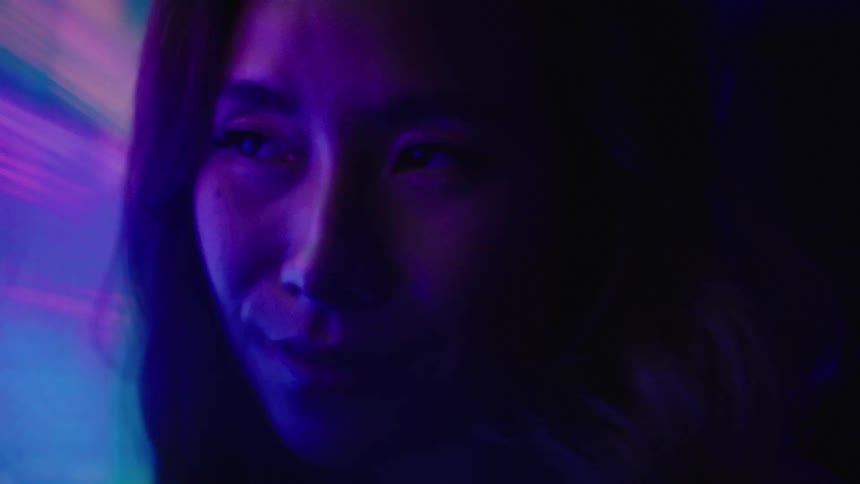 Face lit by neon lights in shades of purple and blue