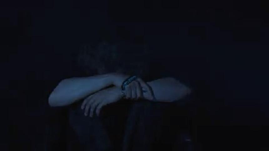 A blurry and abstract view shows a persons hands and arms moving in a dark space with a flashing light passing over them