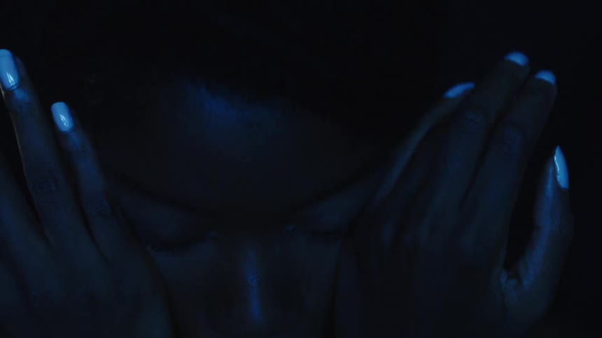 Closeup face with hands on the sides illuminated by blue light