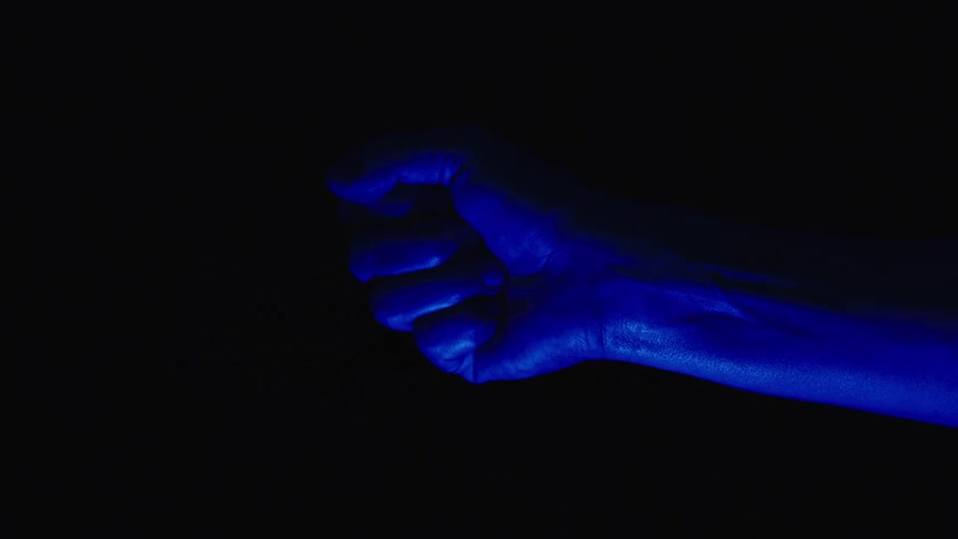 Hand opening and closing in blue light against black background
