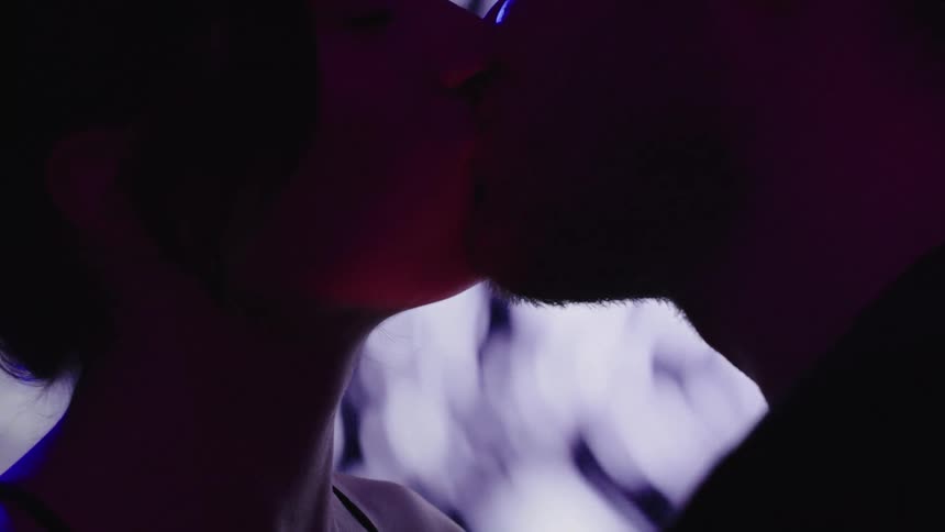Couple kissing under purple and blue lighting