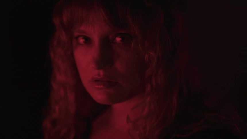 A woman turns her head in the dark looking angry